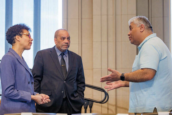 Eve Kelly and Hugh Page, center, speak with an attendee following a Staff Town Hall meeting