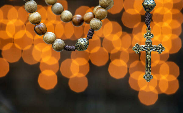 A rosary in front of the lights of candles at the Grotto