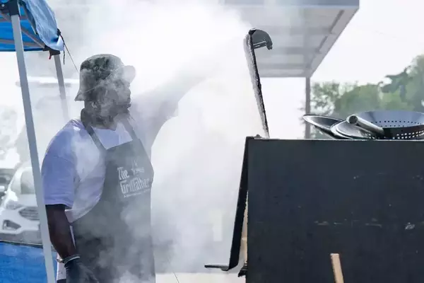 Entrepreneur Raymond Barbour stands in front of his port-a-pit grill while smoke envelopes his face.