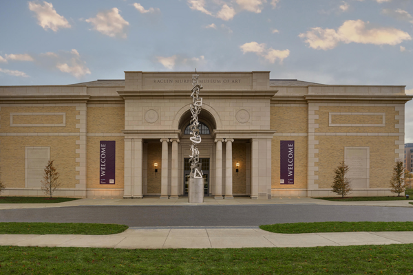 Front facade of a Beaux Arts-inspired art museum with a tall sculpture out front.